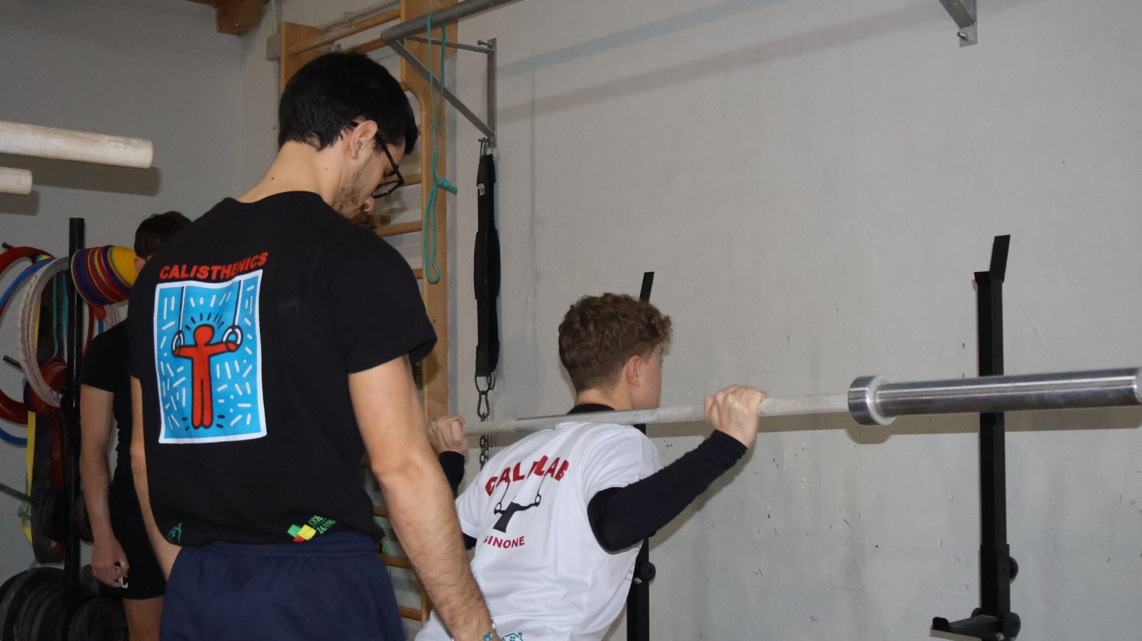 Coach Tecnico Federale assiste l'allineamento e il sovraccarico con bilanciere in sala